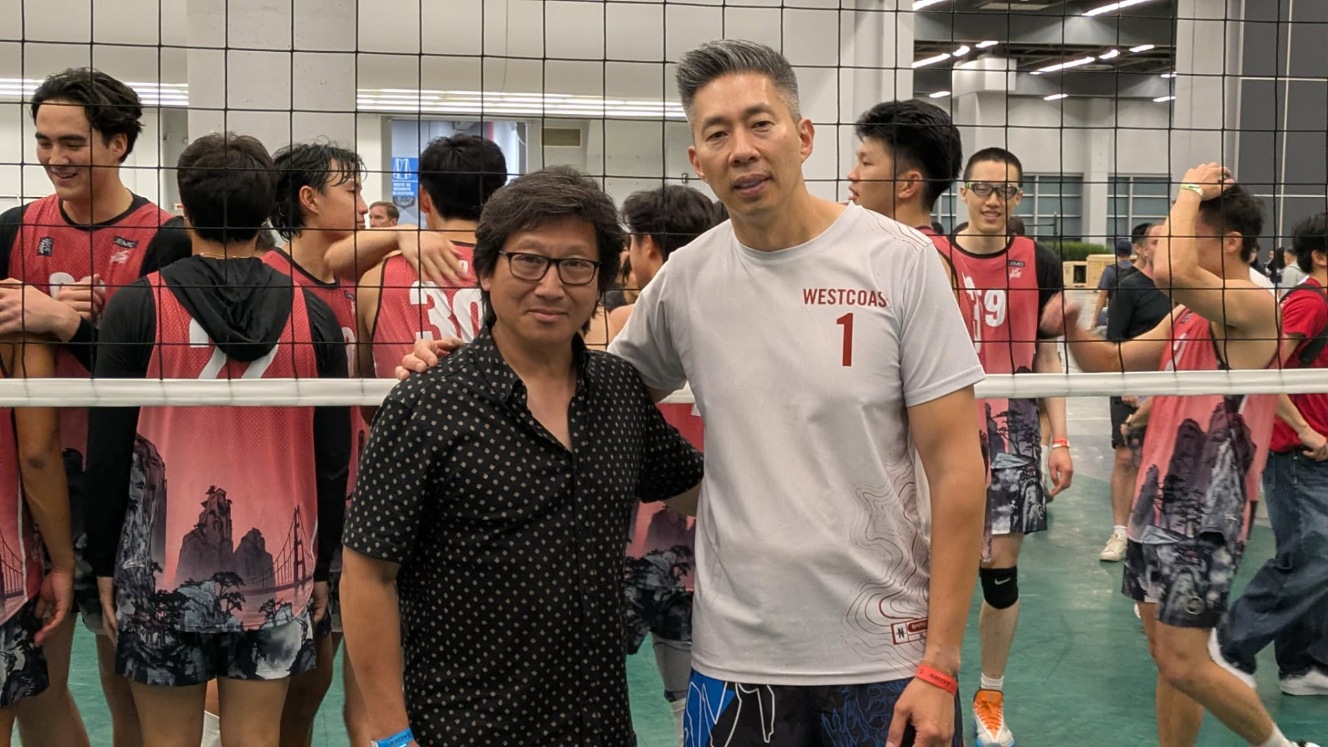 Two organizers standing by the volleyball net at the 81st NACIVT